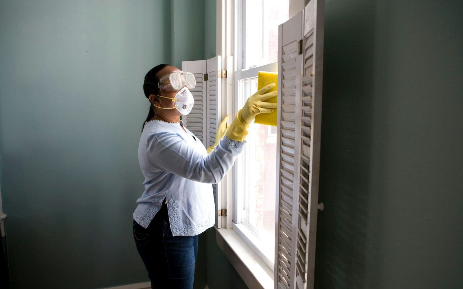 Professional cleaner wiping a window in a New Orleans home